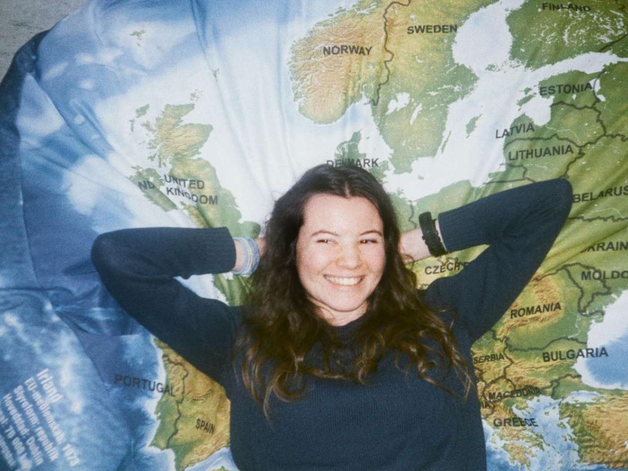 Glad studerende der læner sig op af landkort